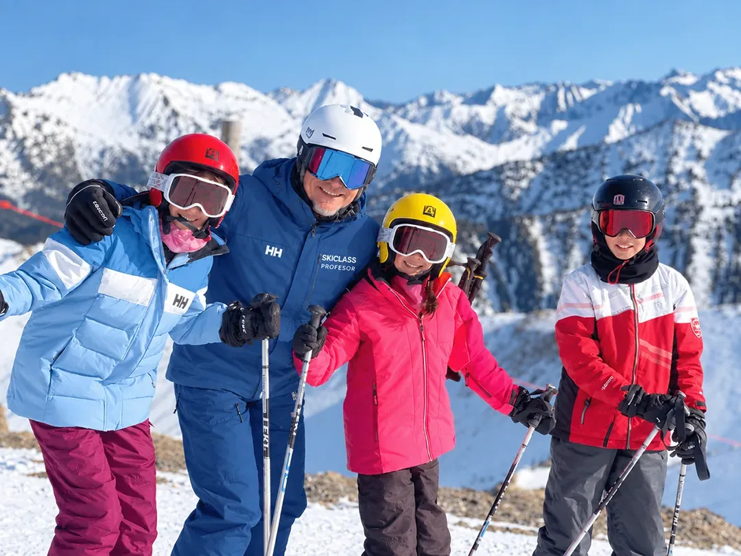 Professor de SkiClass amb tres nens en una classe particular d'esquí davant del Pirineu