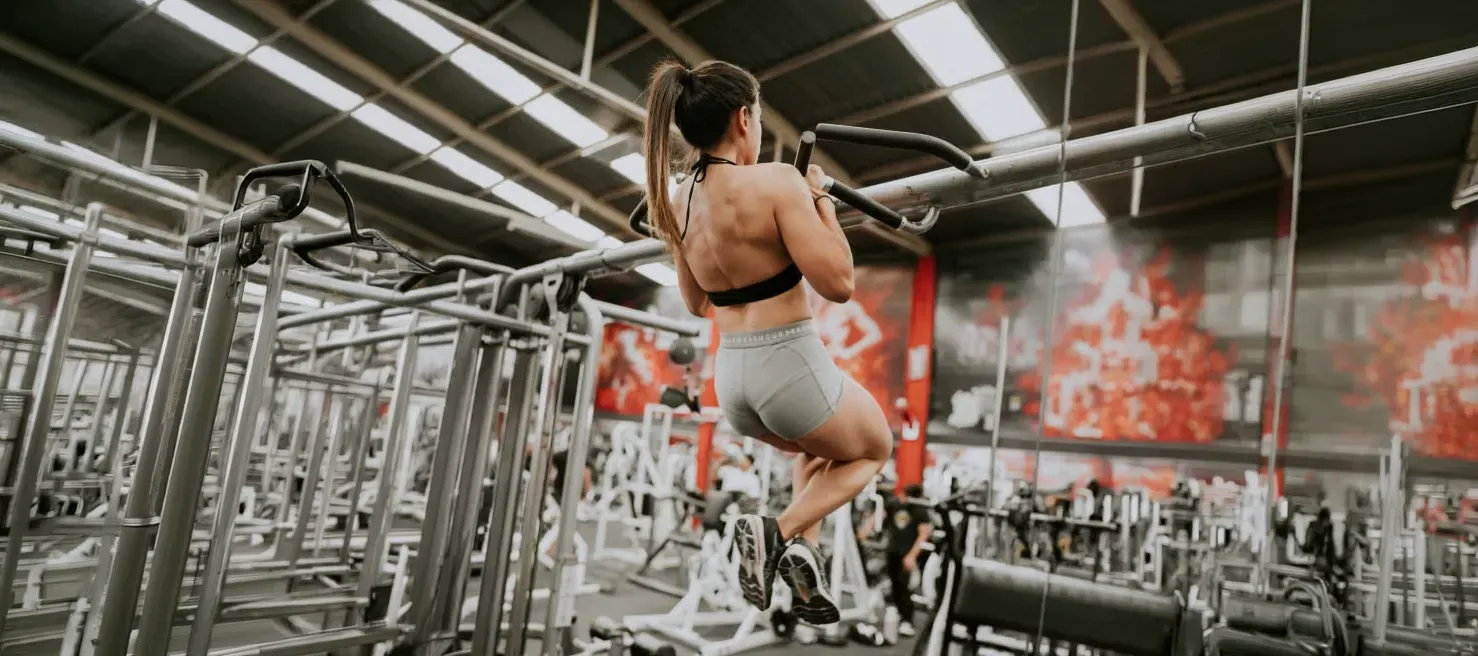 Mujer haciendo dominadas en un gimnasio para prepararse físicamente para la temporada de esquí