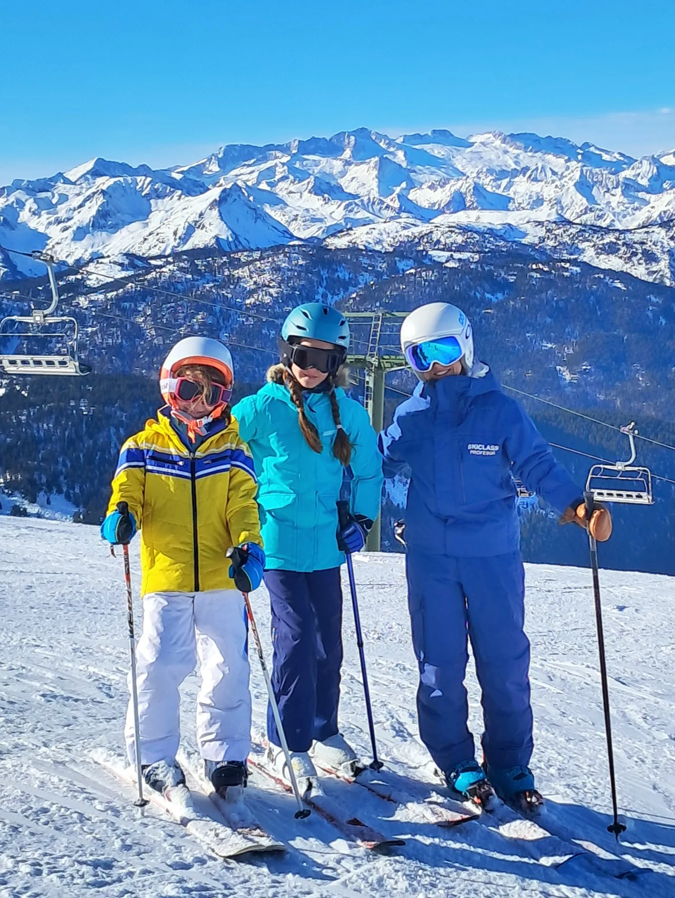 SkiClass instructor with two children skiing in front of the Pyrenees